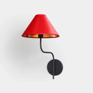 Modern red wall sconce with gold interior and curved black metal arm mounted on white wall