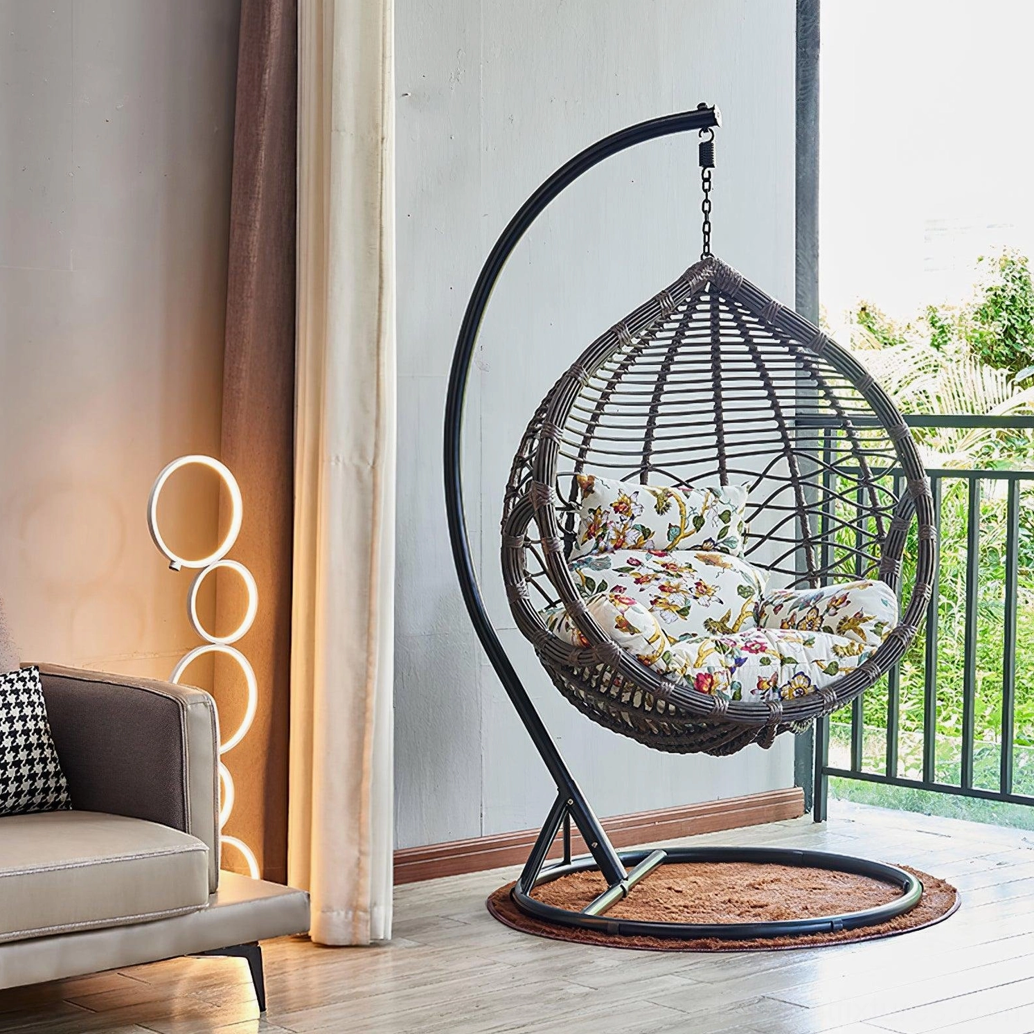 Warm glowing LED ring floor lamp placed beside modern sofa with hanging egg chair in contemporary living room