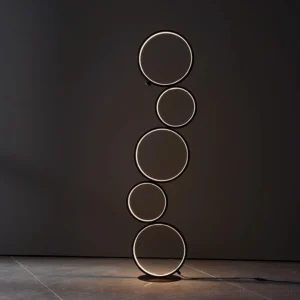 Contemporary circular LED ring floor lamp with glowing light rings on dark marble floor, minimalist modern aesthetic