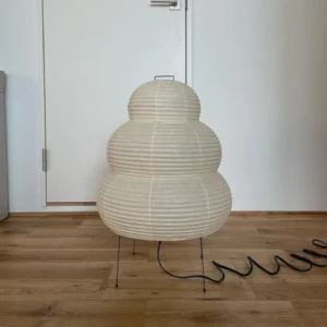 Sculptural tiered paper table lamp rear view, black power cord, unlit minimalist design