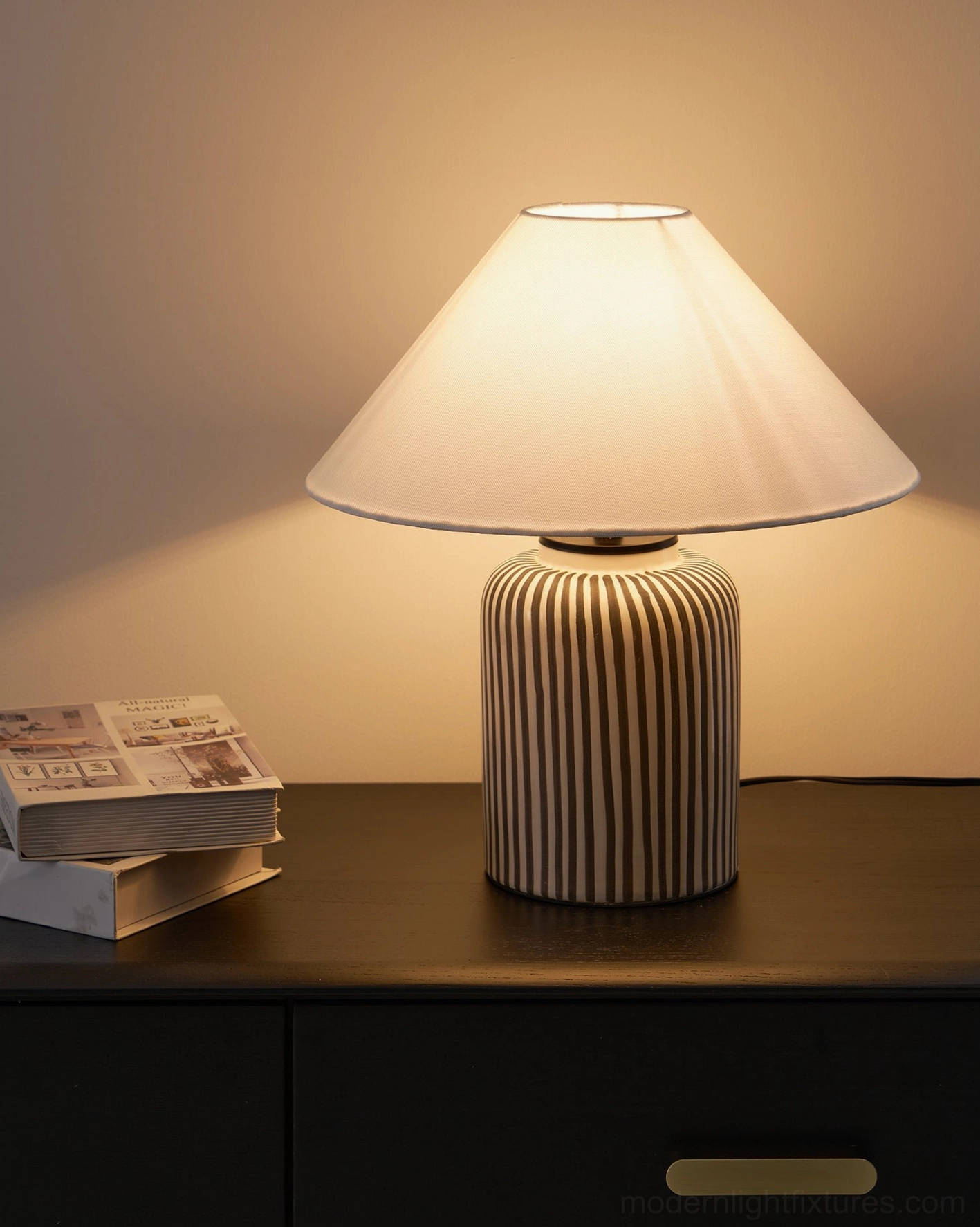 Contemporary striped ceramic table lamp with warm ambient lighting in residential bedroom interior