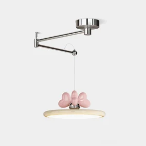 Modern swing arm pendant light with chrome metal arm, beige acrylic disc shade, and pink heart bow accent - front three-quarter studio view