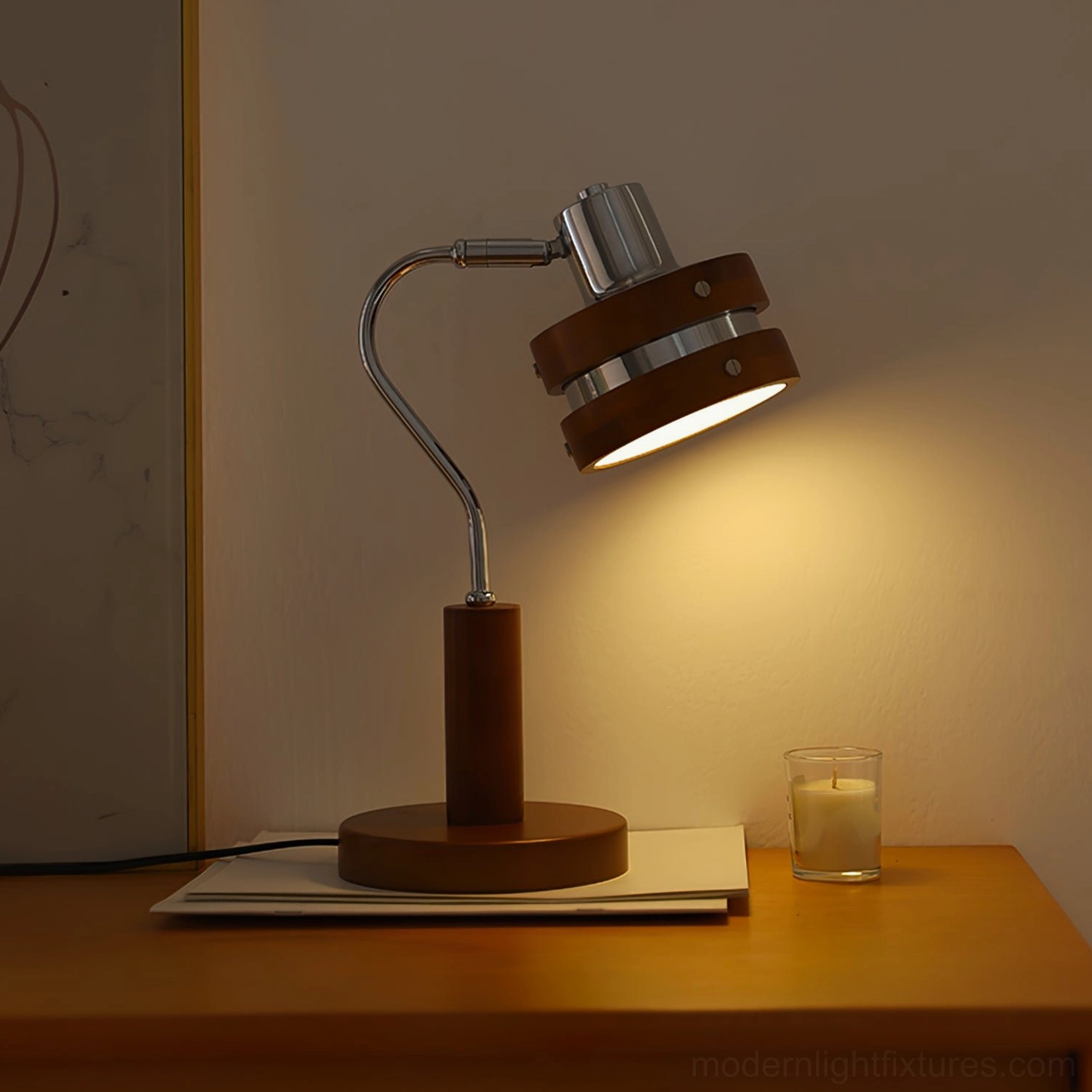 Industrial modern table lamp creating warm ambient lighting in cozy bedroom corner with lit candle and neutral decor