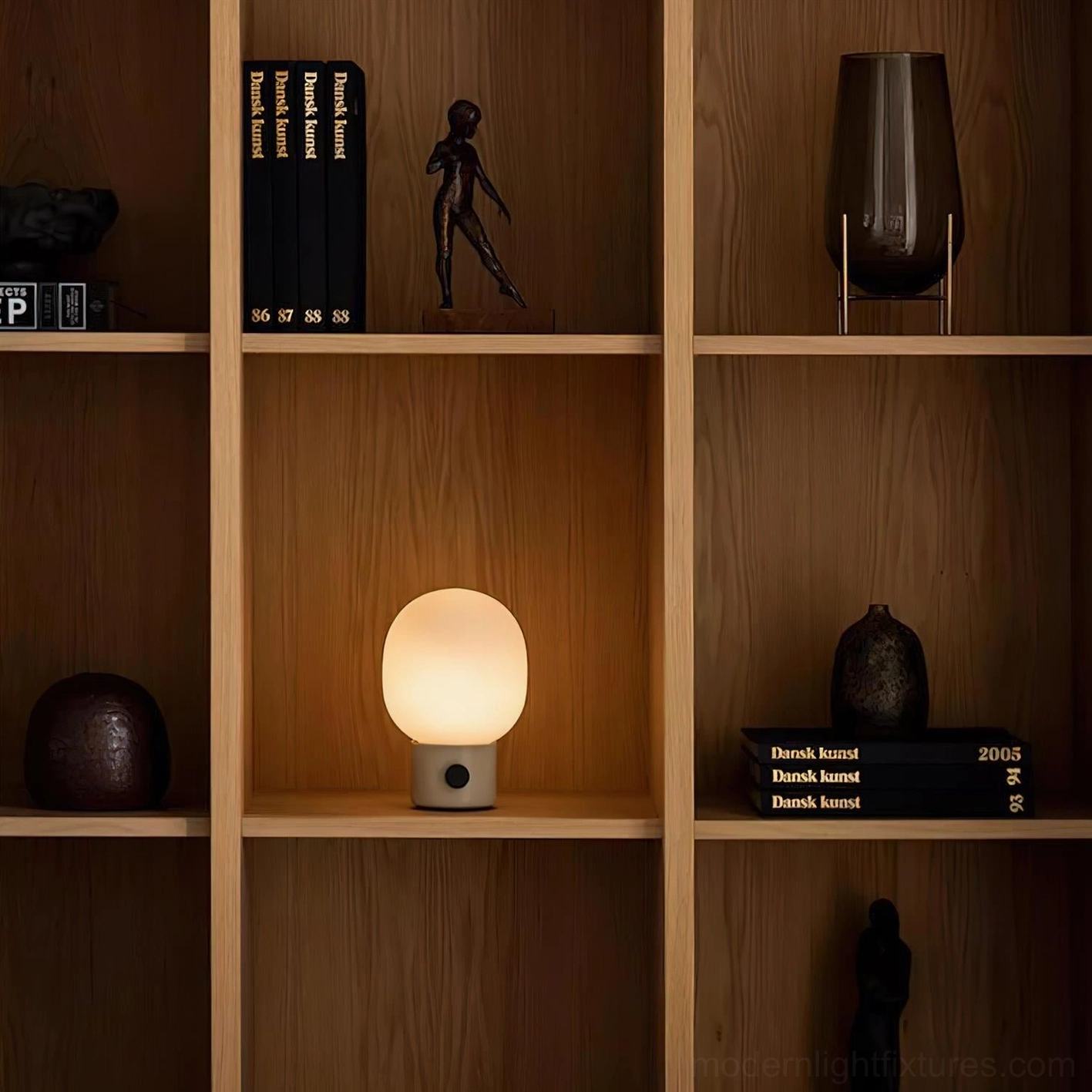 Compact modern table lamp on wooden bookshelf creating warm accent lighting in interior design setting