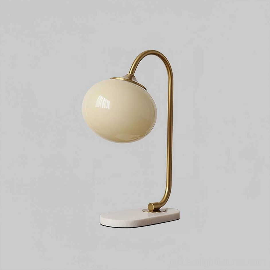 Modern table lamp with globe glass shade, gold frame, and marble base in home office setting