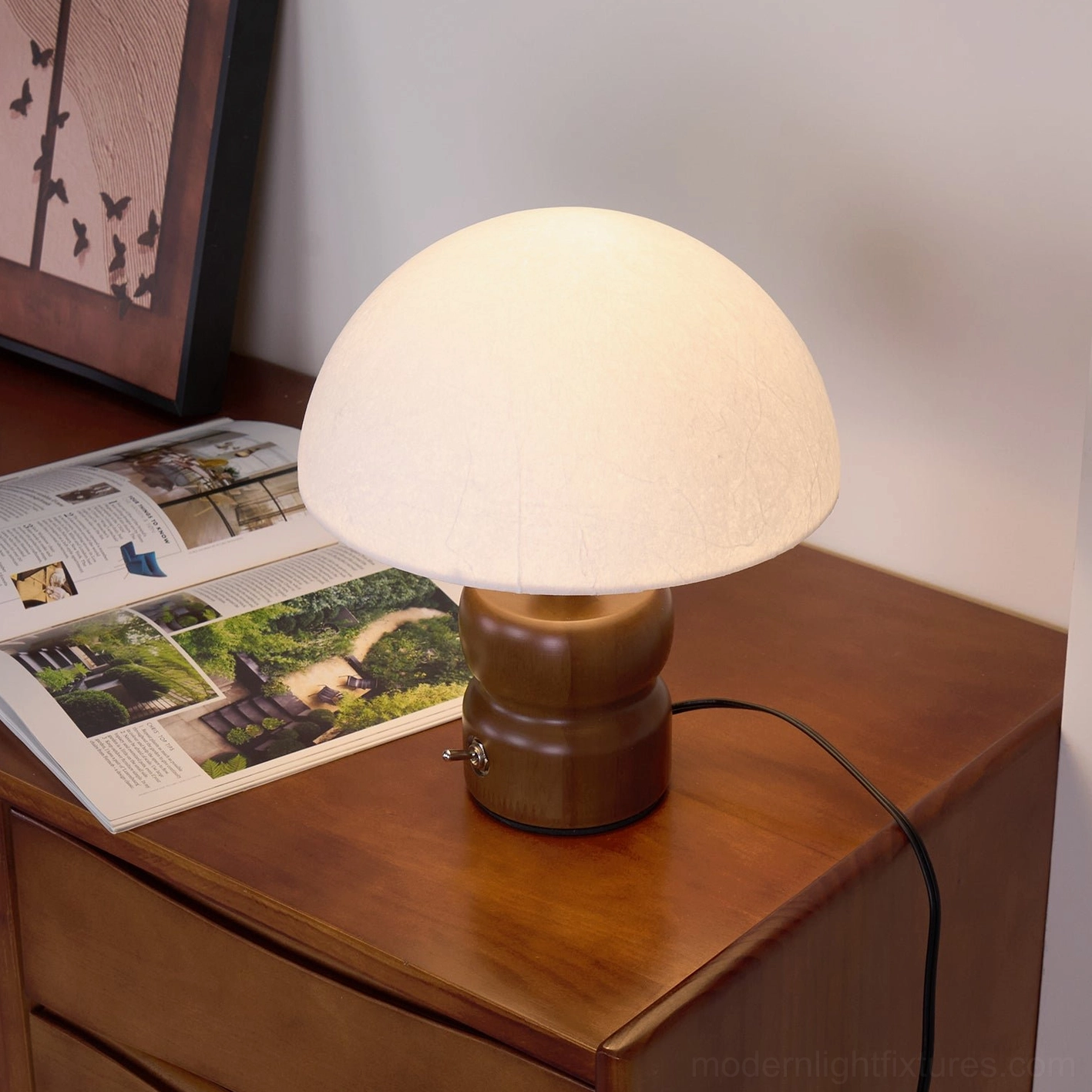 Contemporary mushroom lamp displayed on dark wood side table in living room with framed wall art and magazine