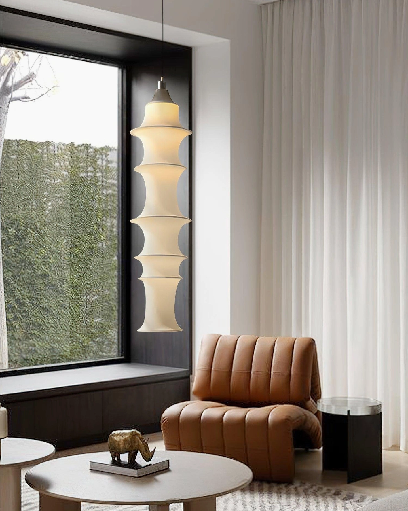 Tiered pendant lamp in modern living room with warm glow beside leather lounge chair