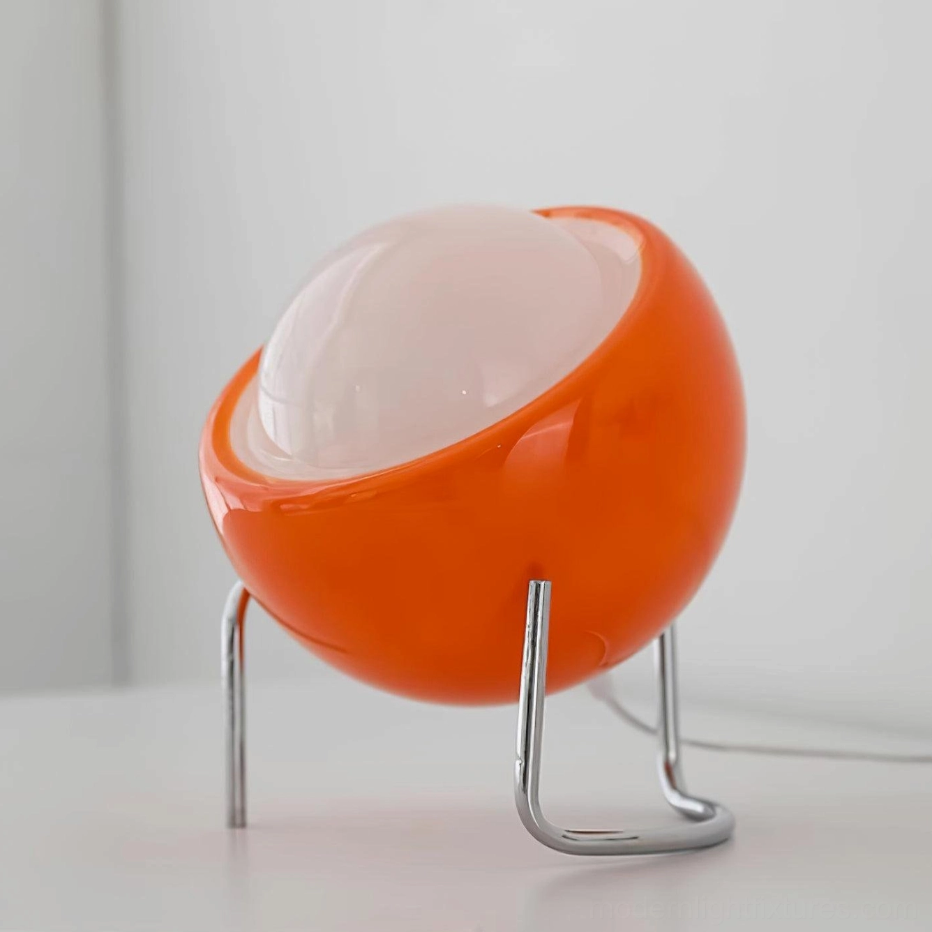 Modern tilted dome table lamp showing curved metal legs and smooth glass sphere construction