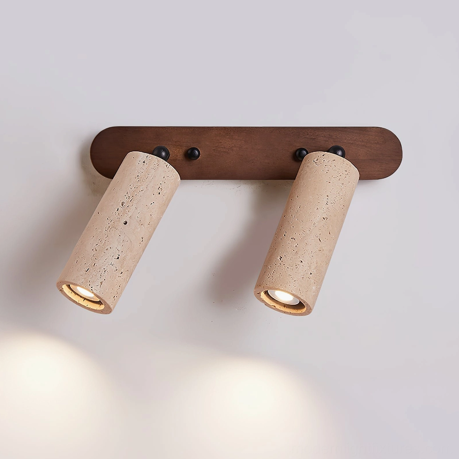 Ricerca 2-head travertine wall sconce low-angle view showing tiltable cylindrical stone shades and light distribution