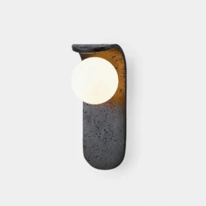 Modern travertine wall sconce with opal glass diffuser, front studio view showing dark speckled stone base and frosted globe shade
