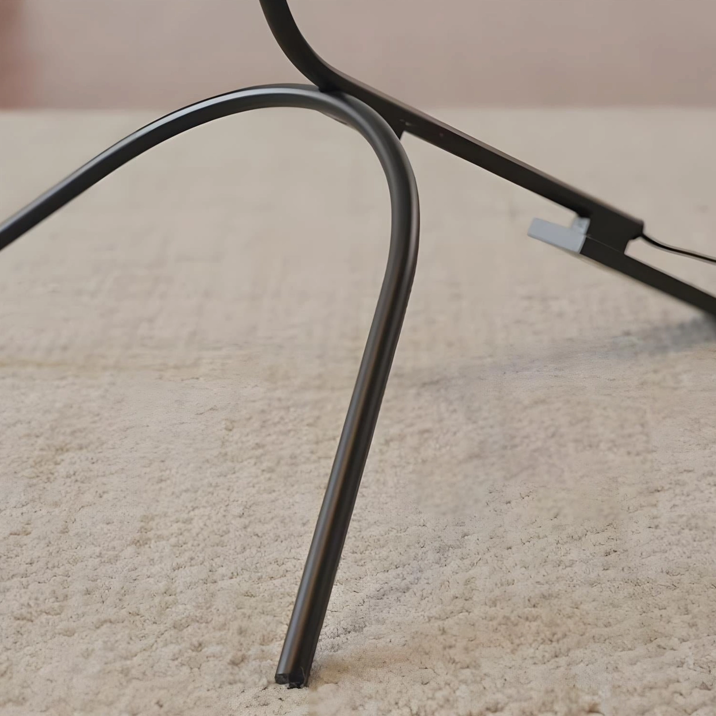 Modern tripod arc floor lamp close-up of base design, three-prong stability feature, foot switch control detail
