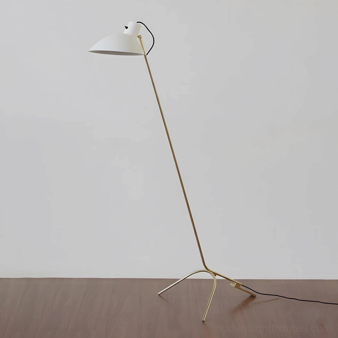 Contemporary tripod floor lamp brushed gold finish with white dome shade on wood floor, elegant three-prong base