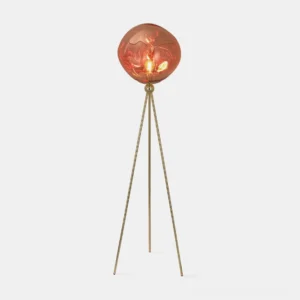 Modern tripod floor lamp with molten lava glass shade in studio setting, featuring brass gold frame and reddish-brown artistic glass