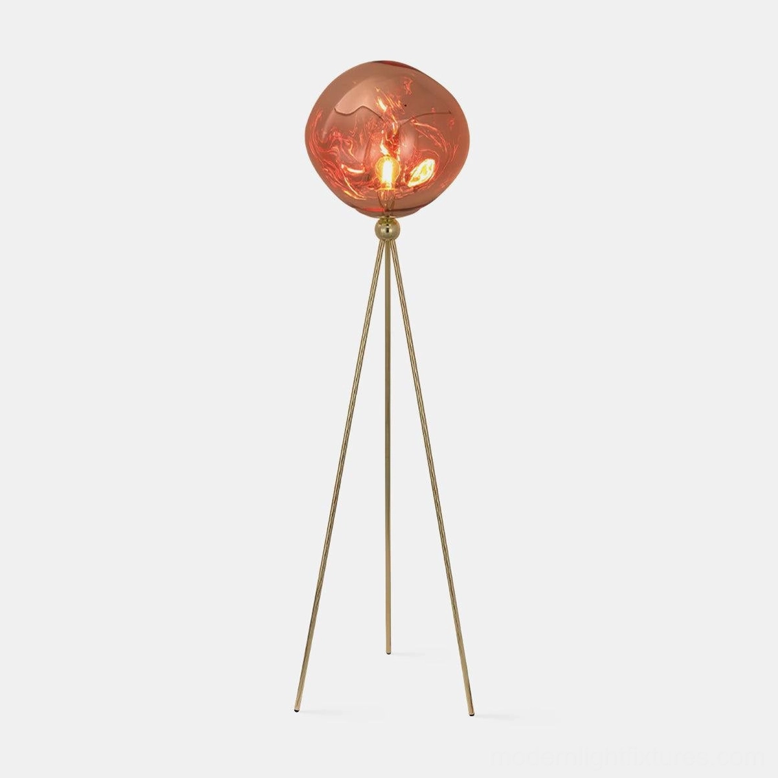 Modern tripod floor lamp with molten lava glass shade in studio setting, featuring brass gold frame and reddish-brown artistic glass