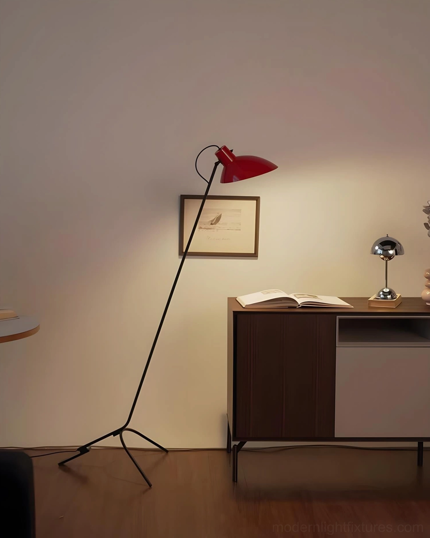 Modern tripod floor lamp with red shade positioned in warm home study environment with wooden cabinet and soft lighting