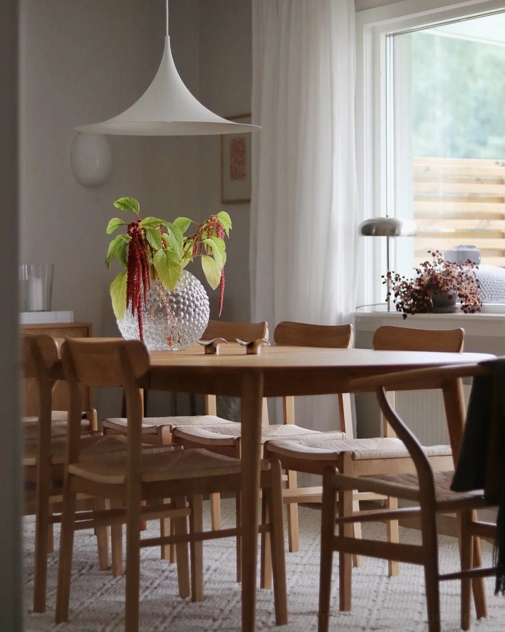 Modern white trumpet swing arm pendant in bright dining room with natural daylight