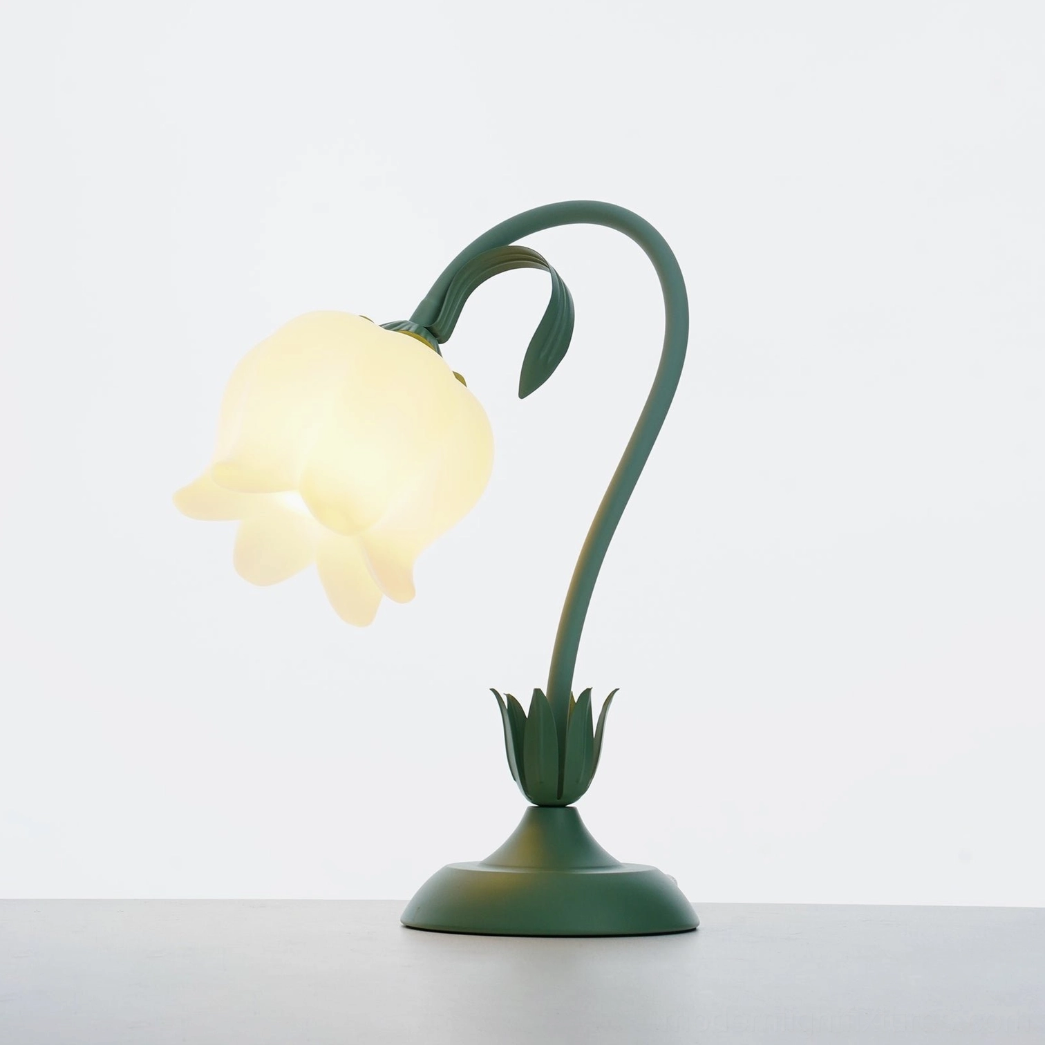 Modern twist tulip table lamp with fully illuminated creamy frosted shade and organic floral base