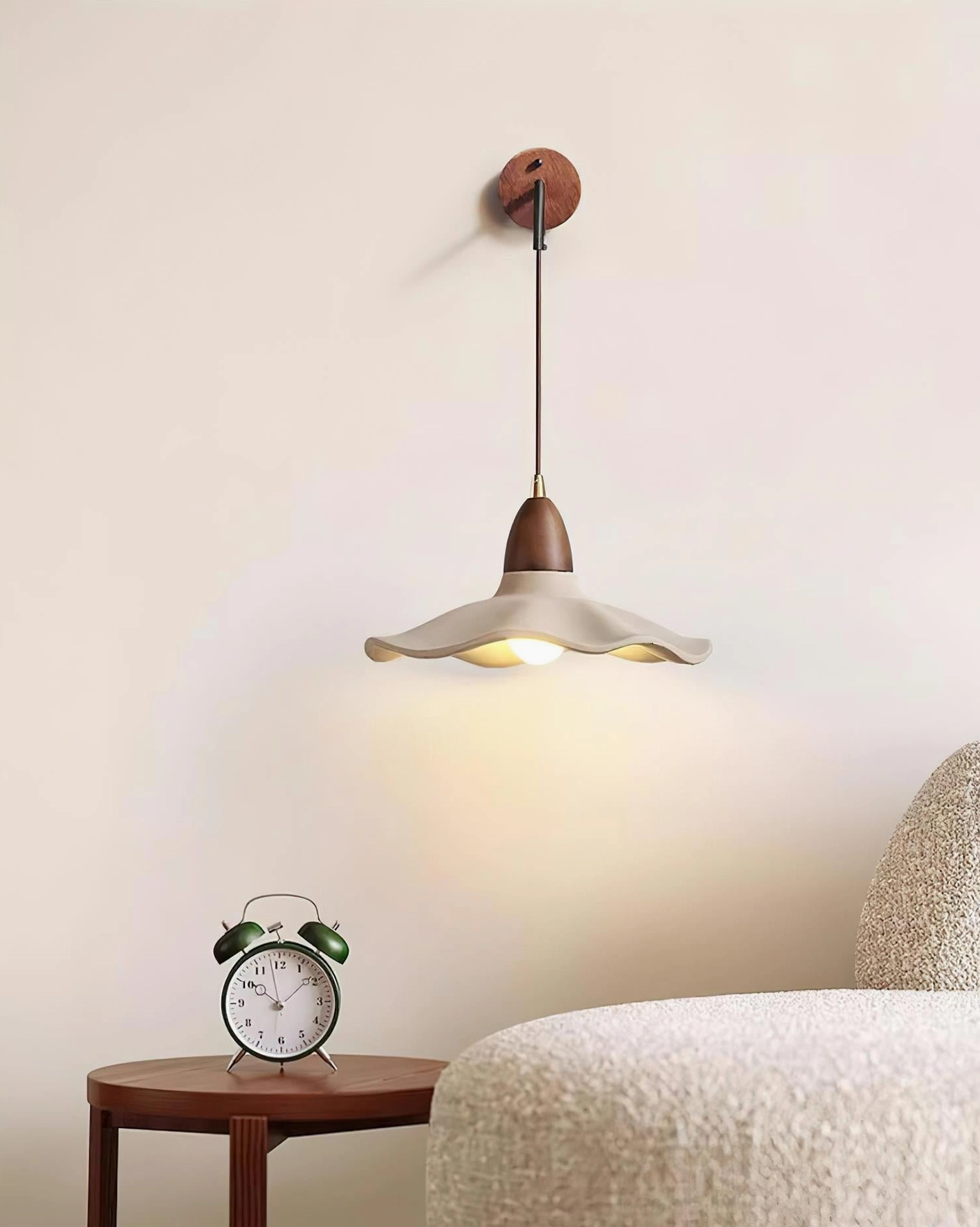 Crested wave wall sconce installed beside wooden bedside table with vintage alarm clock in warm bedroom lighting