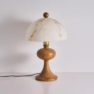 Modern wood table lamp with marble-veined alabaster shade and brass accents, three-quarter view displaying natural wood grain and power cord