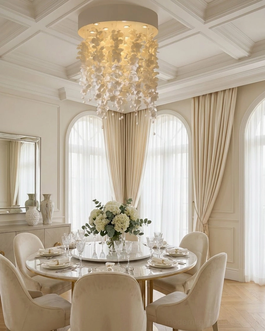 High-end white ceramic petal chandelier hanging in luxurious French dining room with coffered ceiling and warm yellow lighting