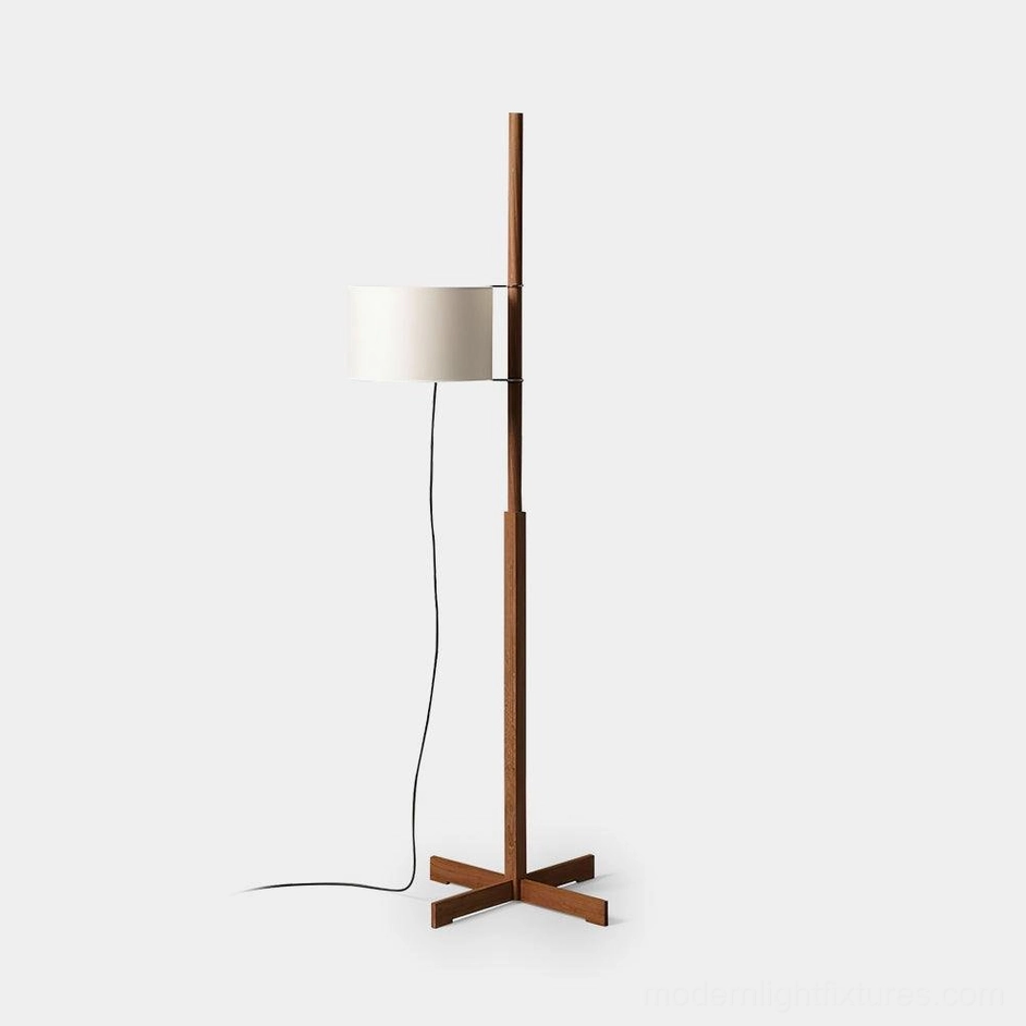 Modern minimalist wood floor lamp with white fabric drum shade and cross metal base, front studio view