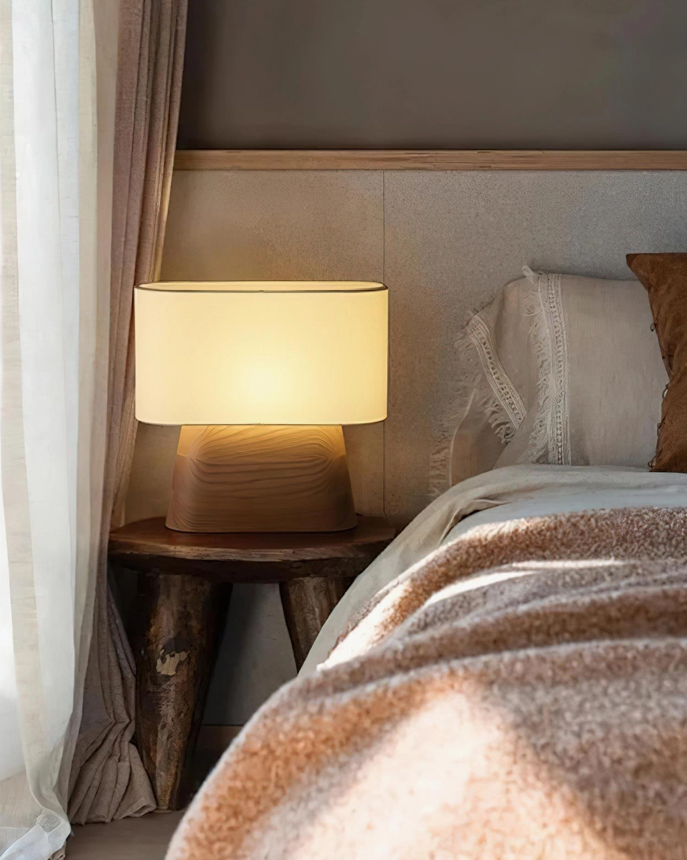 Cozy bedside table lamp emitting warm light beside fabric headboard in rustic bedroom
