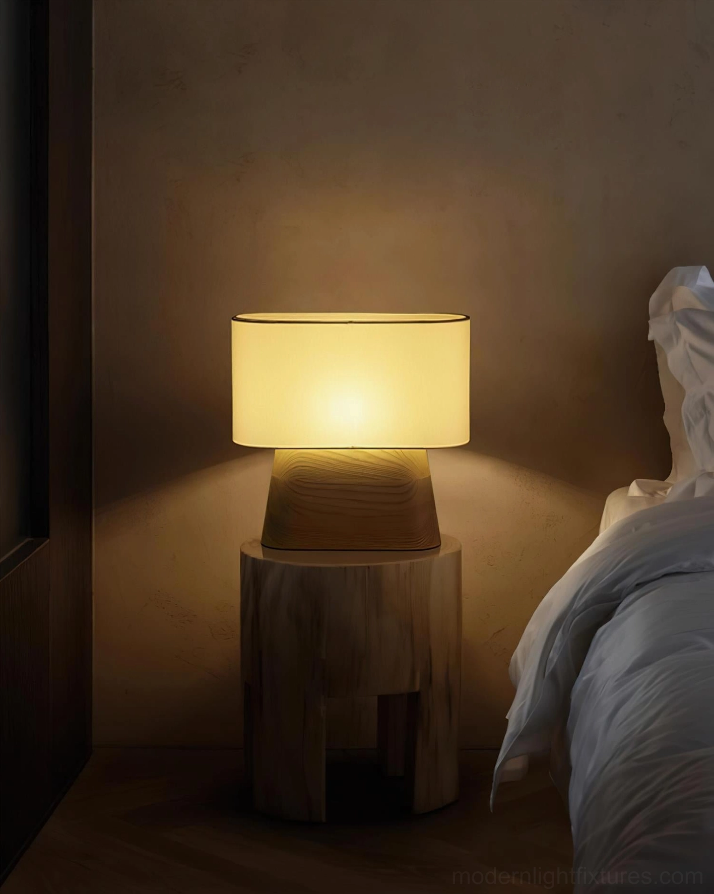 Warm bedside table lamp with fabric shade glowing on wooden nightstand in minimalist bedroom