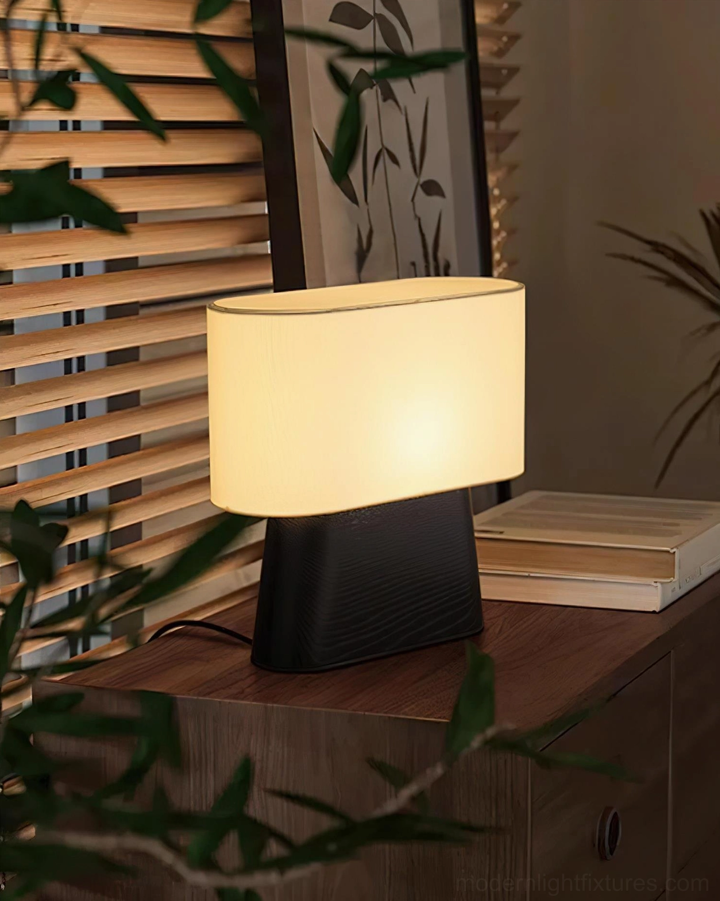 Contemporary table lamp with beige shade and black wood base on side table, oblique angle