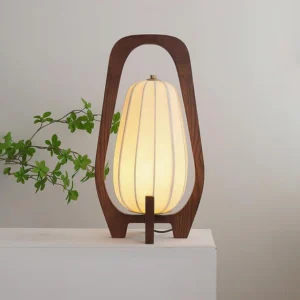 Nordic wooden table lamp with warm ambient glow on minimalist white table with green foliage, wabi-sabi rustic style lighting