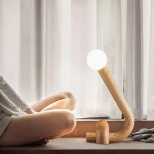 Natural wood table lamp illuminated on residential windowsill workspace, warm ambient LED light for home office