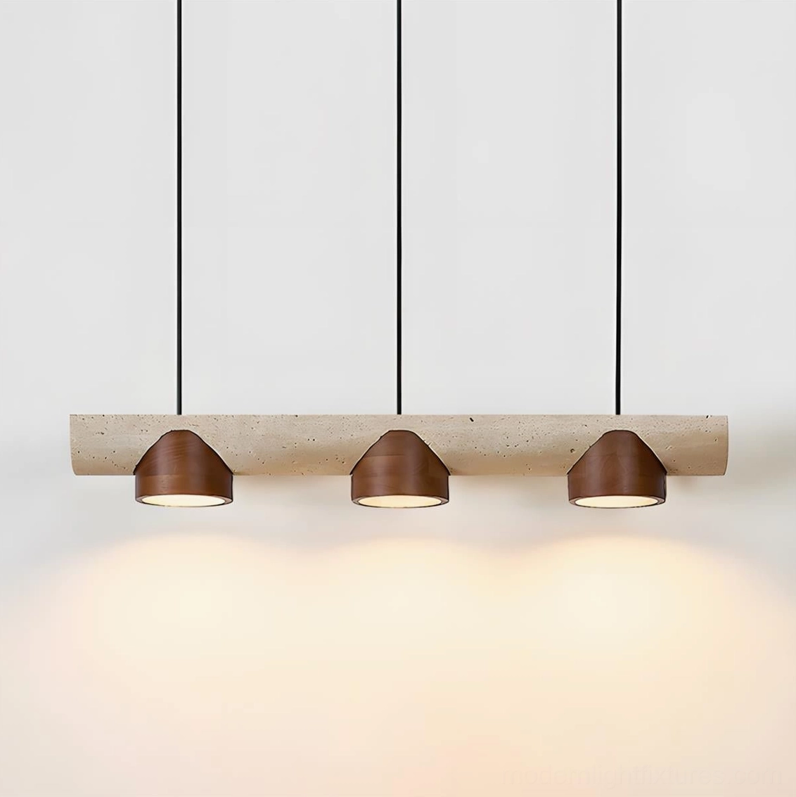 Three-light linear pendant chandelier with warm ambient lighting showcasing travertine base and minimalist design