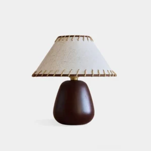 Molino ceramic table lamp with linen shade front view, displaying conical stitched shade and dark rounded ceramic base