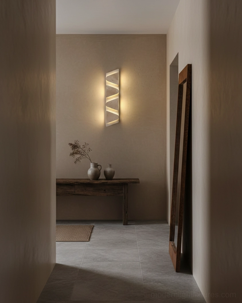 Monolith wall sconce installed in minimalist entryway hallway creating warm ambient light