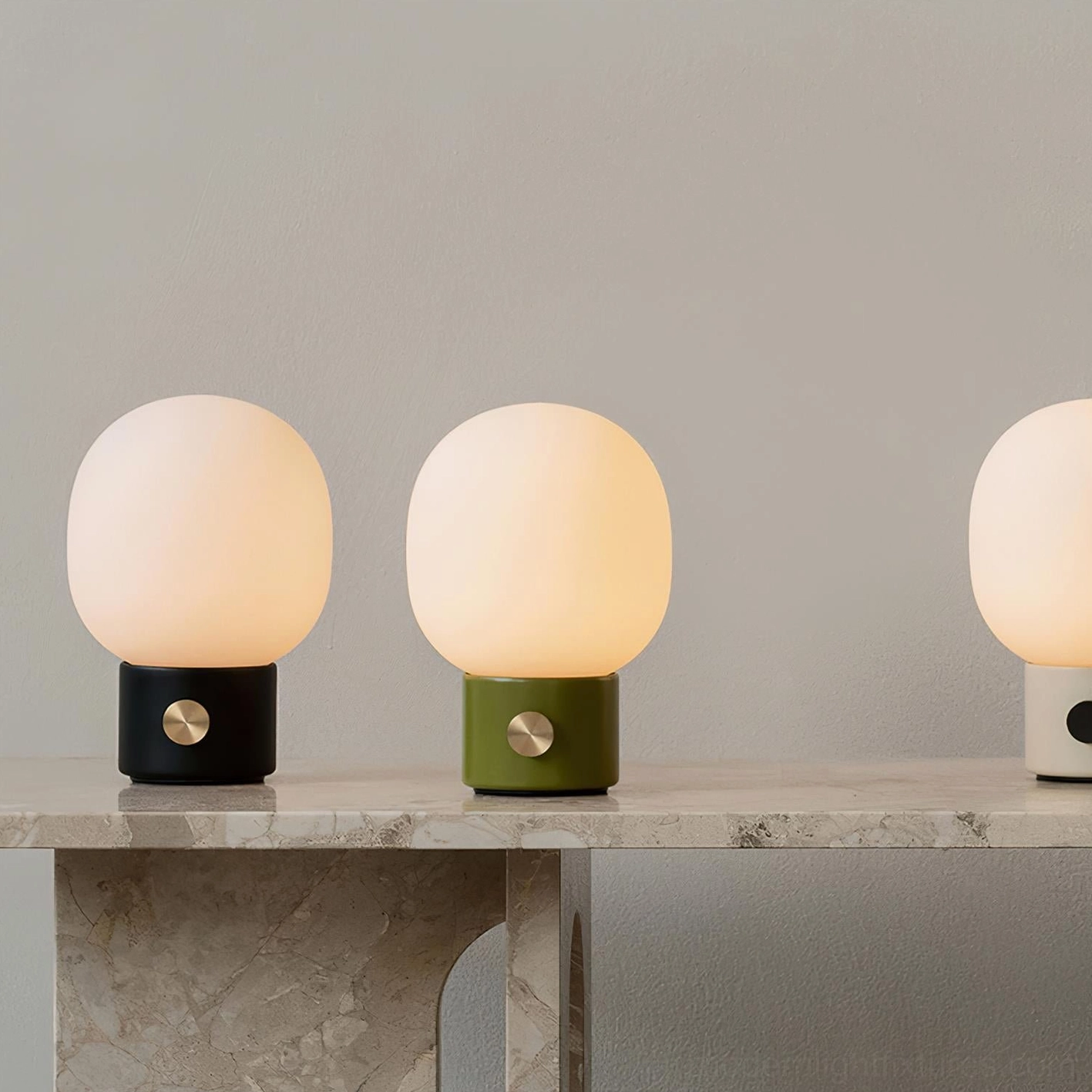 Multiple Monolith table lamp variants with frosted glass shades in gold black and white finishes on marble console