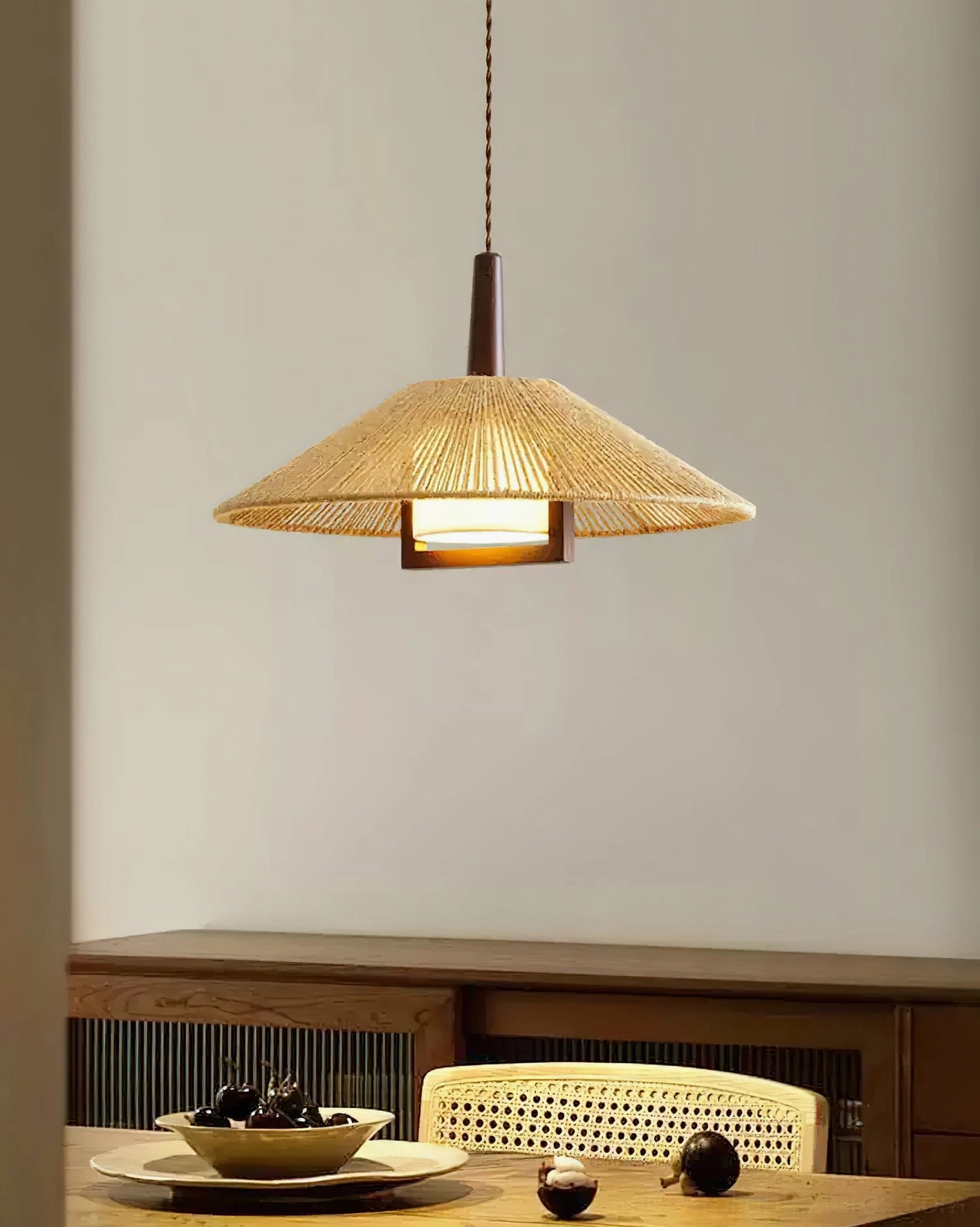 Mons rattan pendant light installed above dining room with wooden sideboard and table setting