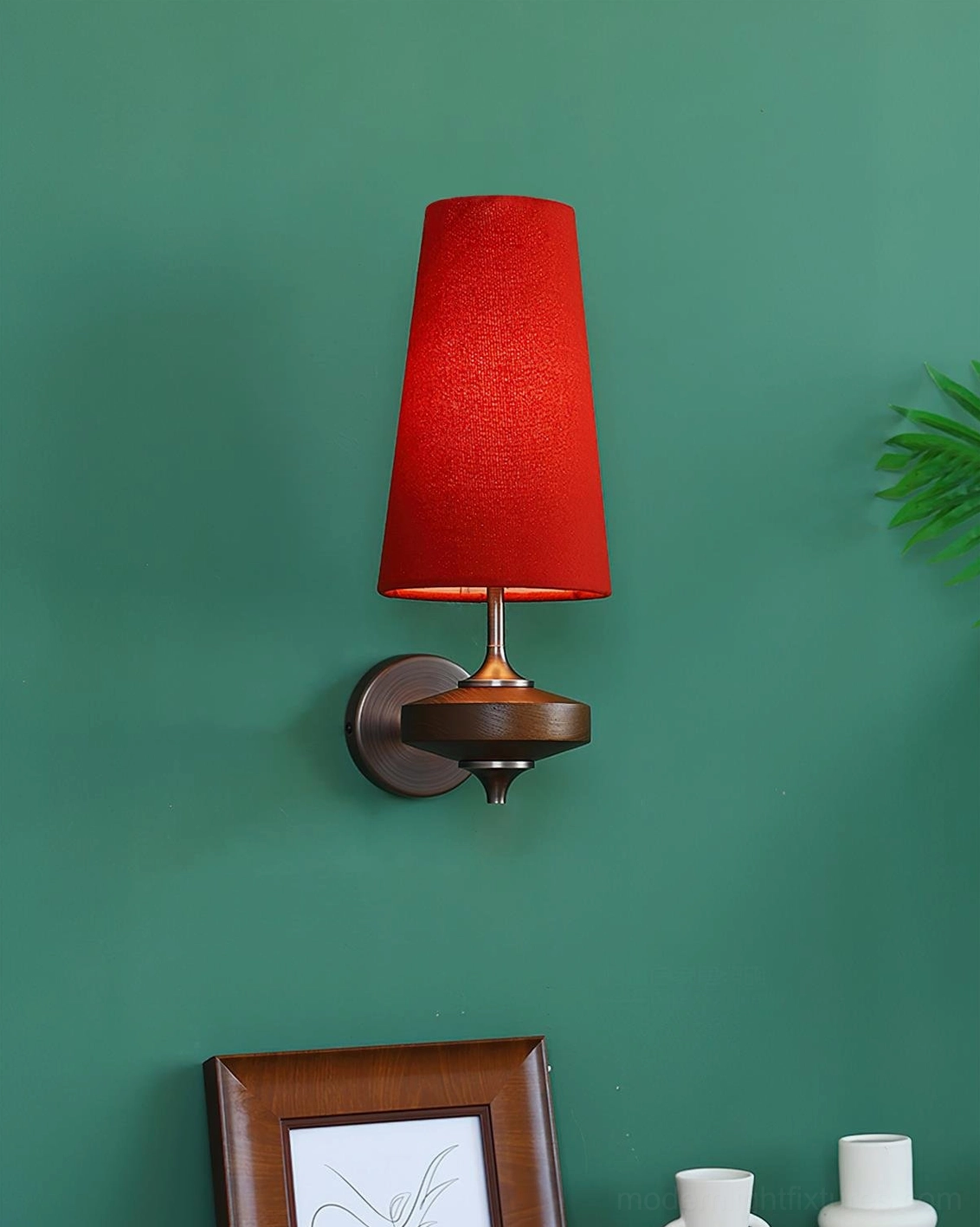 Montera mid-century modern wall sconce with red fabric shade and bronze base mounted on green accent wall with home décor