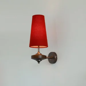 Montera modern wall sconce with bold red conical shade and antique brass metal base, front view against light gray wall