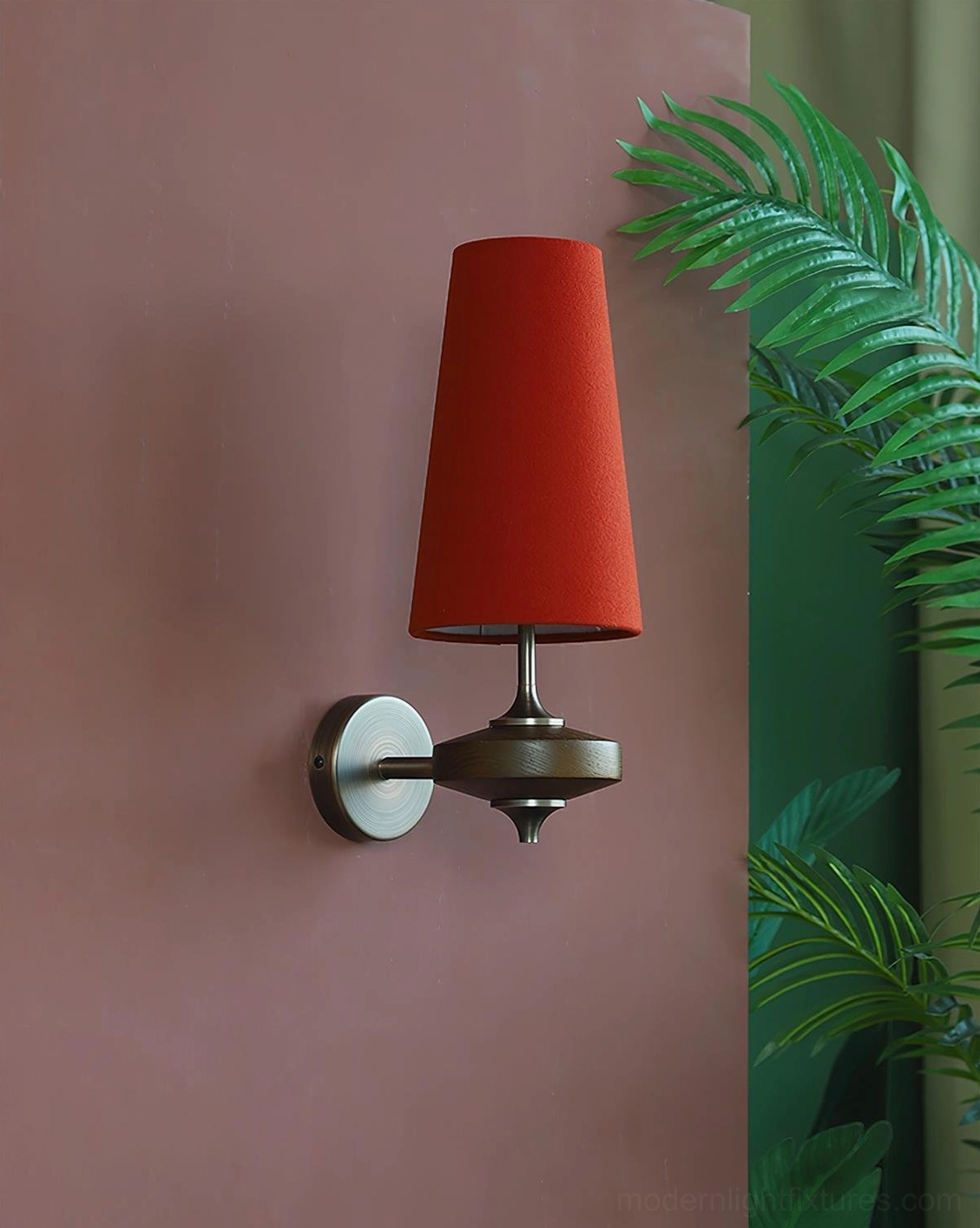 Lit Montera mid-century wall sconce with bold red fabric shade and light bronze base on terracotta wall with botanical décor