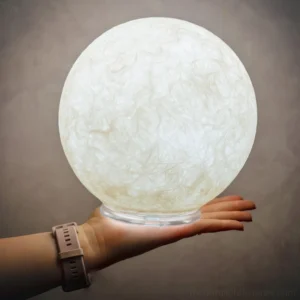 Moon table lamp held in hand overhead view showing base and warm white glowing light