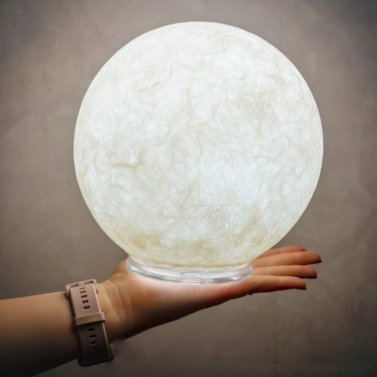 Moon table lamp held in hand overhead view showing base and warm white glowing light