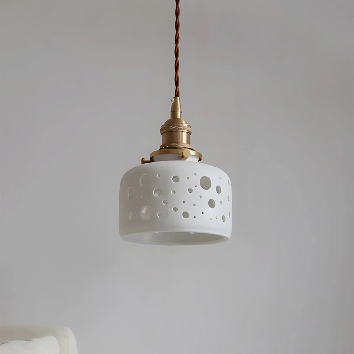 Modern Moonveil pendant light with random circular perforations on matte white ceramic shade and brass fittings