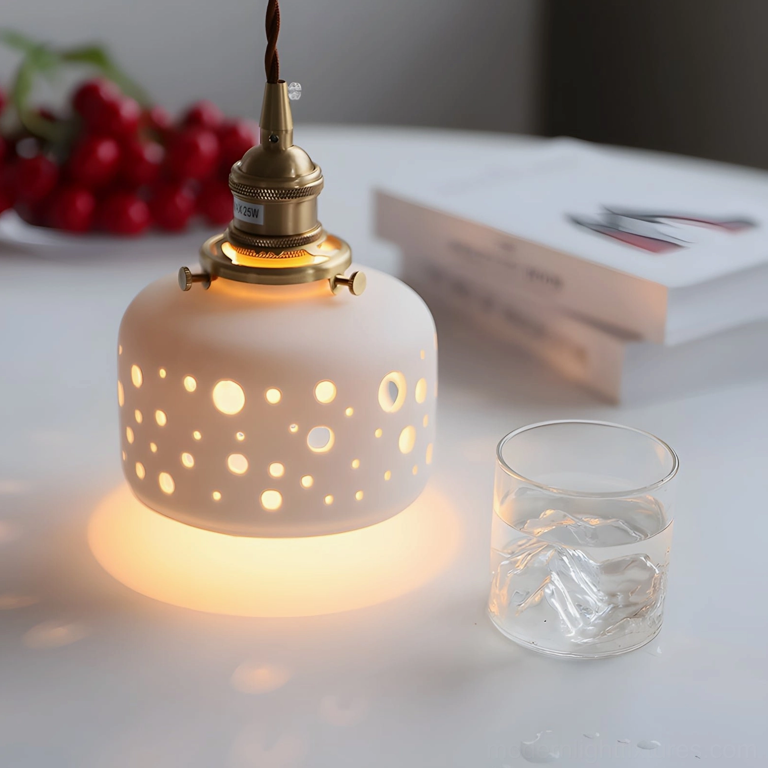 Warm glowing Moonveil pendant light above dining table with books and fresh fruits, creating layered shadow effects
