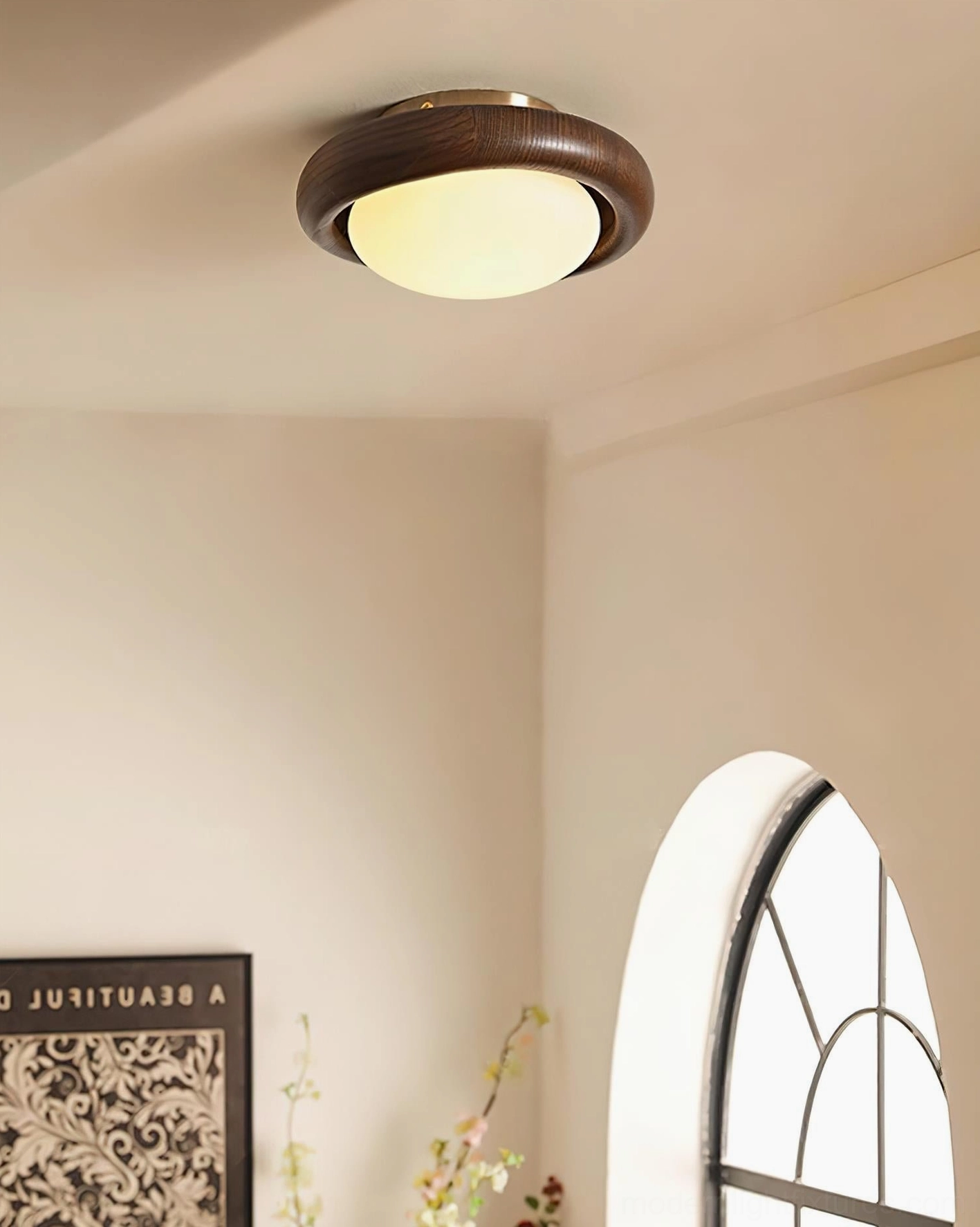 Ceiling light fixture installed in corner room above arched window nook with decorative accent wall