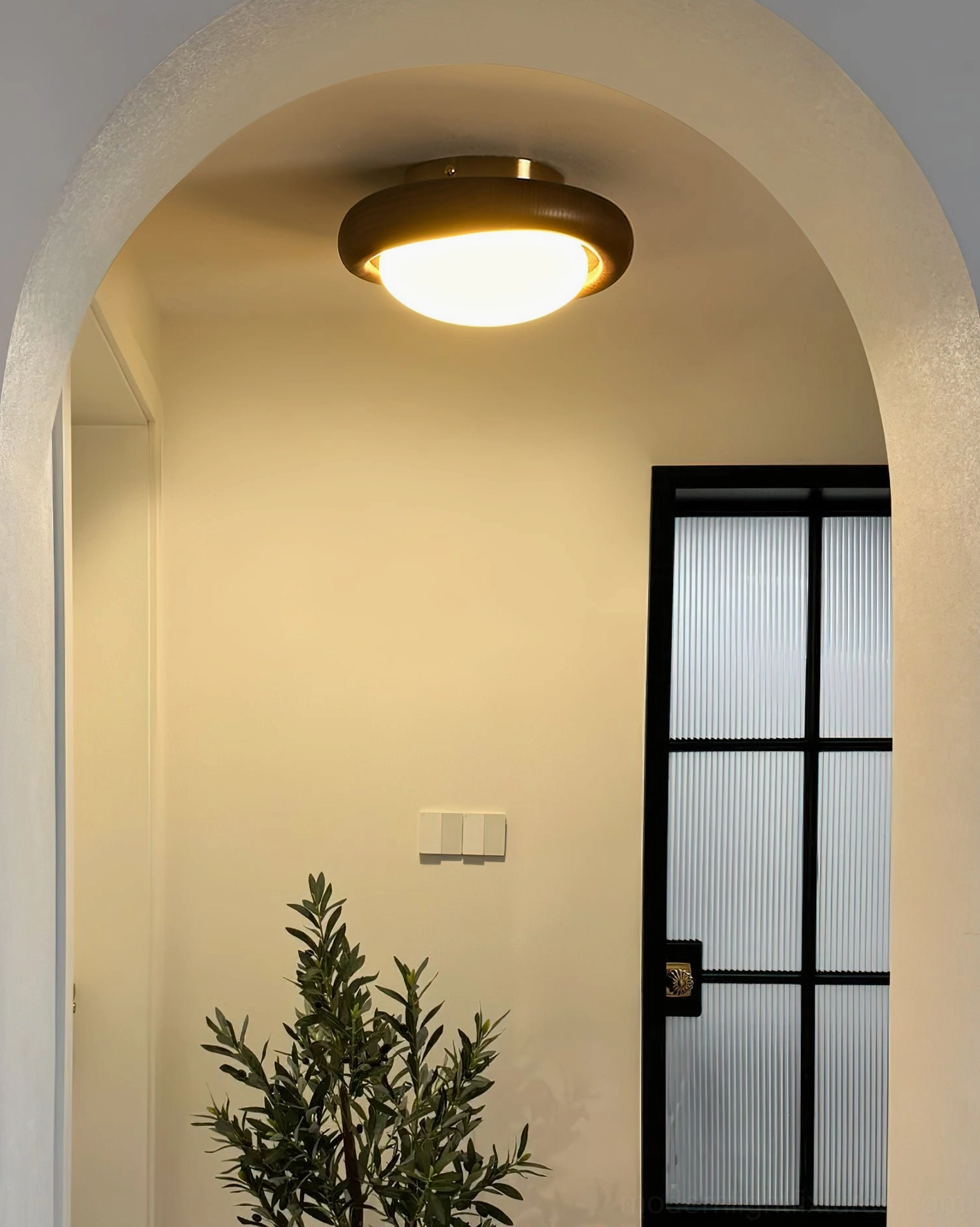 Flush mount ceiling lamp installed in arched doorway passage emitting warm ambient lighting
