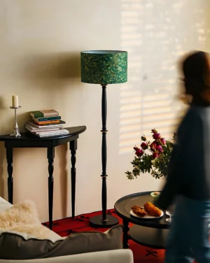 Artistic mosaic floor lamp in retro living room interior, three-quarter rear angle showing green shade and black stand beside side table
