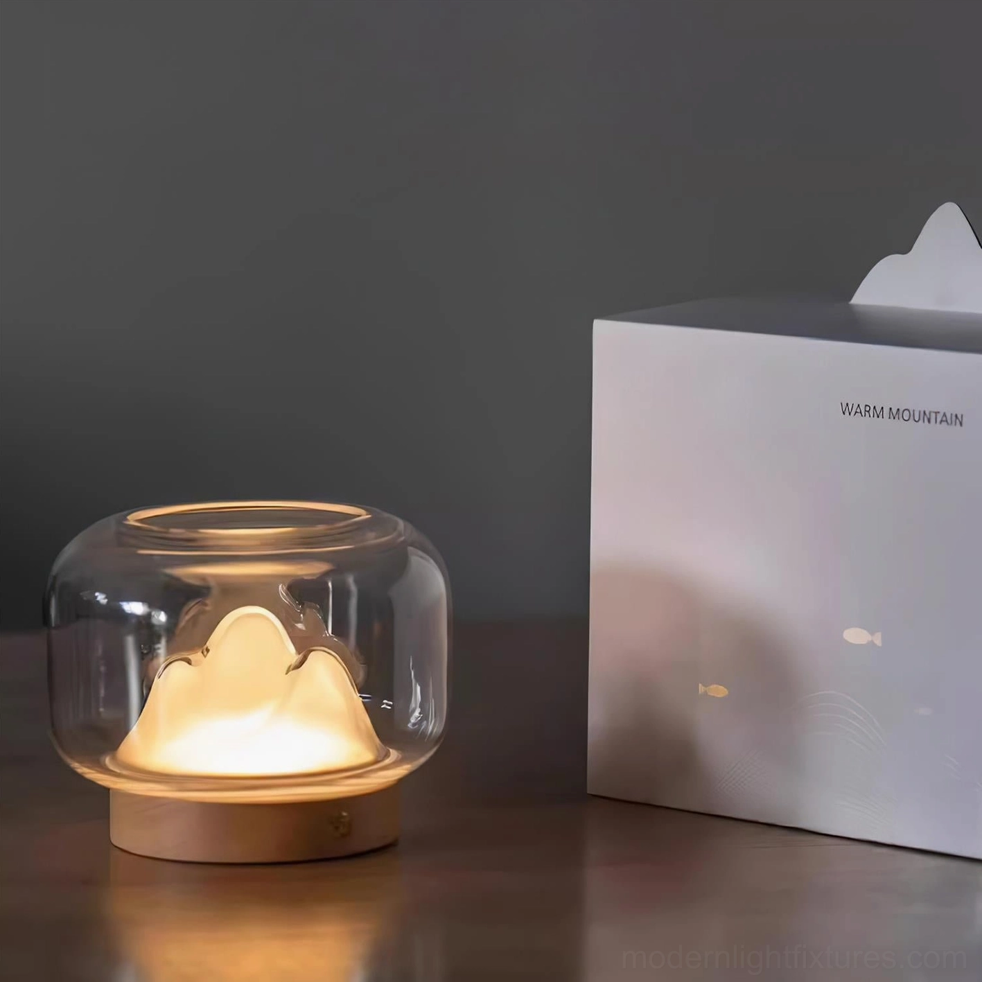 Mountain table lamp detail shot, wood base grain texture and clear glass enclosure, 3000K warm white LED technology