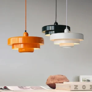 Three-color tiered pendant lights in orange, white, and green showing color variant options on minimalist tabletop display