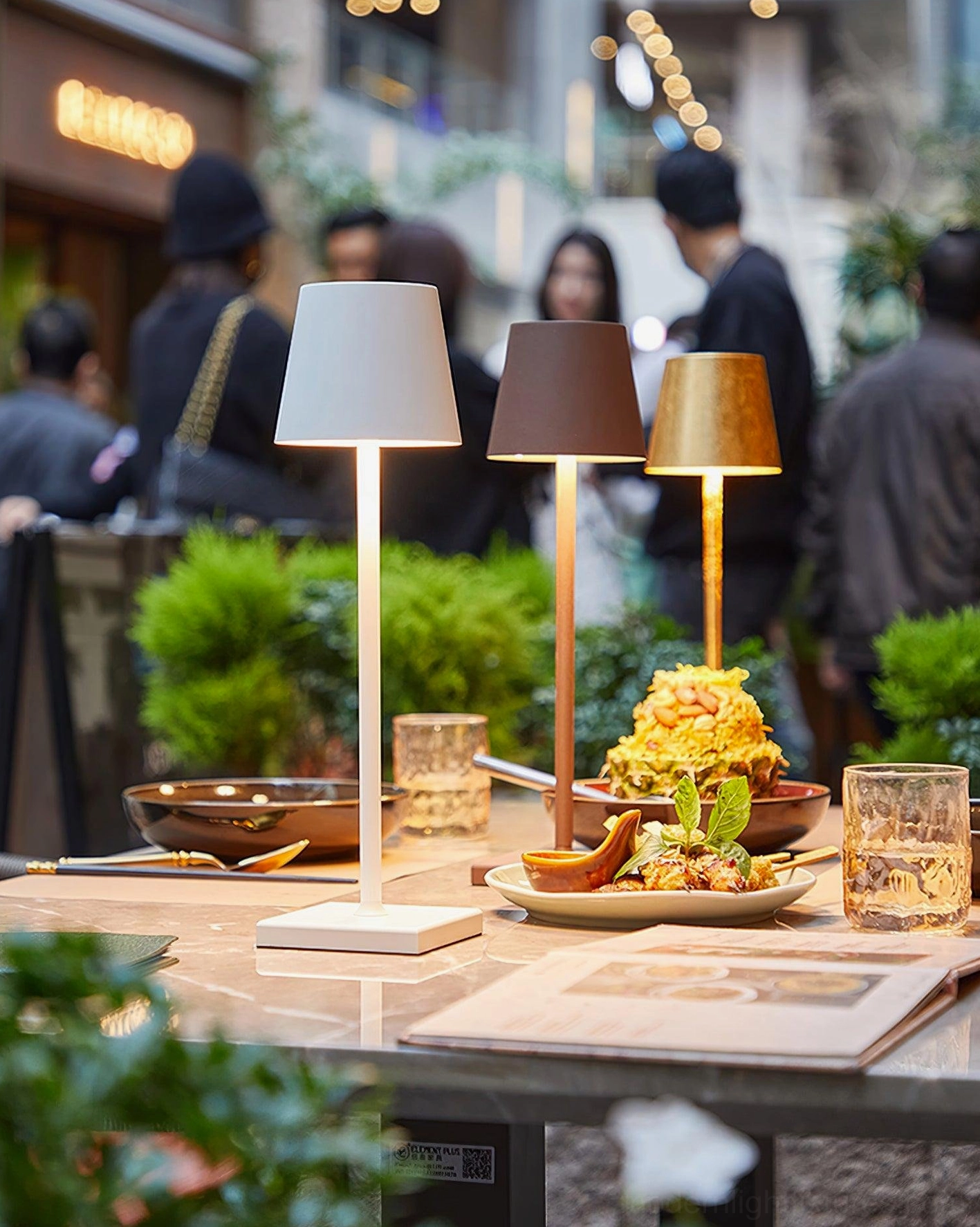 Multi-color integrated LED table lamps with various metal finishes in outdoor cafe dining scene