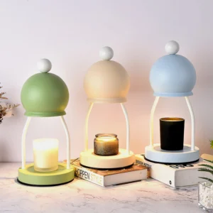 Three-pack candle warmer lamps in sage green, beige, and light blue on marble table with books and decorative accents