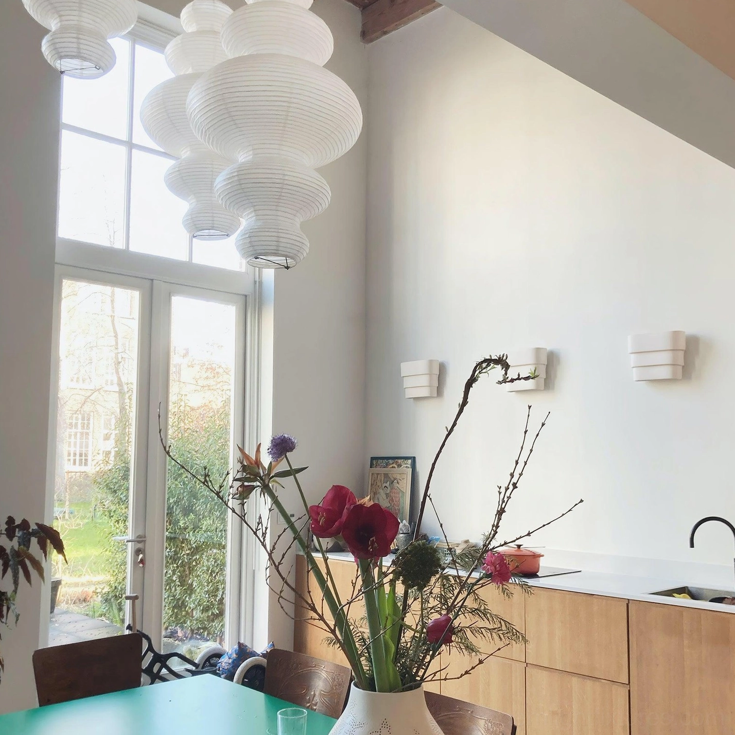 Multiple white sculptural pendant lights clustered in modern kitchen dining area creating layered composition